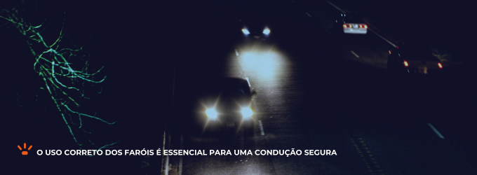 Veículos com os faróis ligados trafegando em uma estrada sem iluminação.